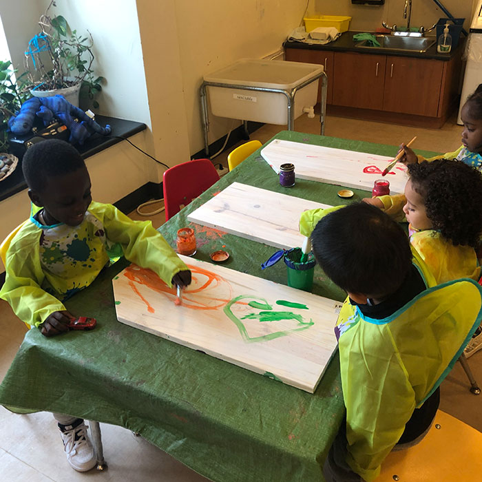 Four children painting at a table