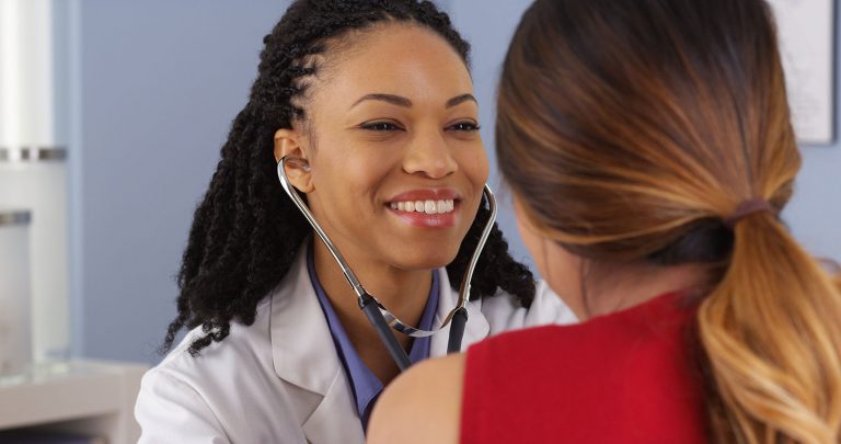 Smiling doctor listening to her patient's heart