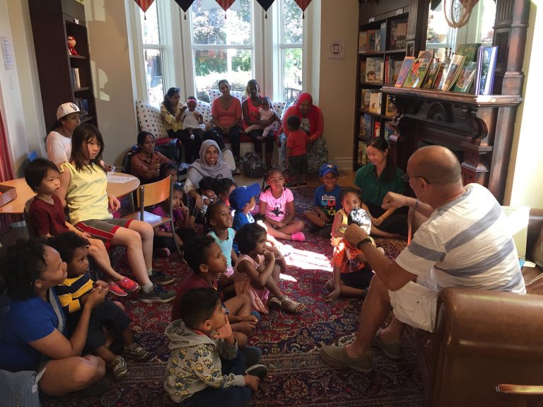 An educator teaching to a group of kids in a living room