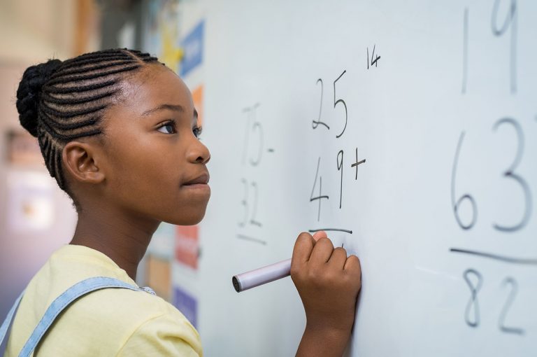 A pre-school student solving math equations on the white board
